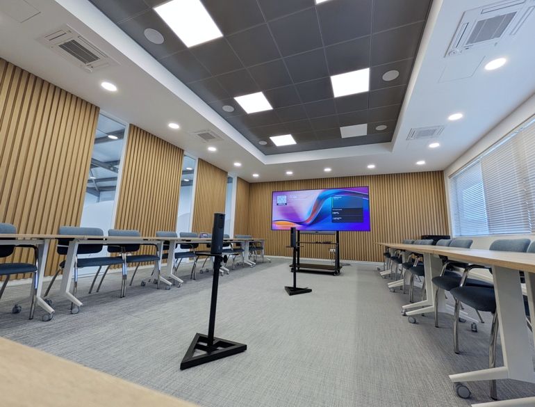 Modern conference room set up for a presentation with a large screen on a stand at the front.