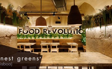 Restaurant dining area with wooden tables and benches, a back wall greenery, and a large 'FOOD REVOLUTION' sign.