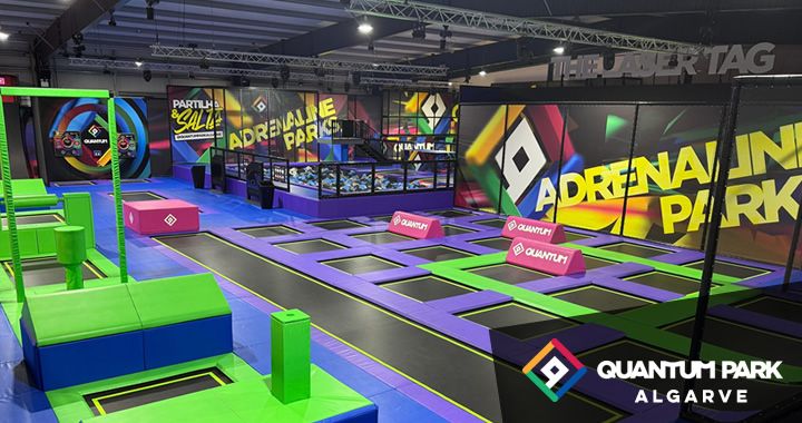 Indoor trampoline park with purple and green trampolines, foam blocks, and neon wall art; Quantum Park Algarve branding visible.